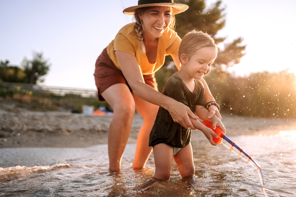 Mother and cute little toddler playing with fishing toy on the sea